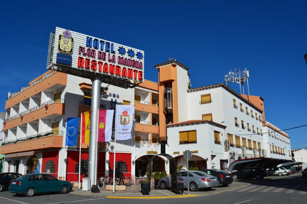 un edificio con coches estacionados en un estacionamiento en Hotel Flor de la Mancha en La Roda