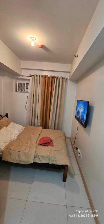Un dormitorio con una cama y un televisor de pantalla plana. en Northpoint CozyHome, en Davao City