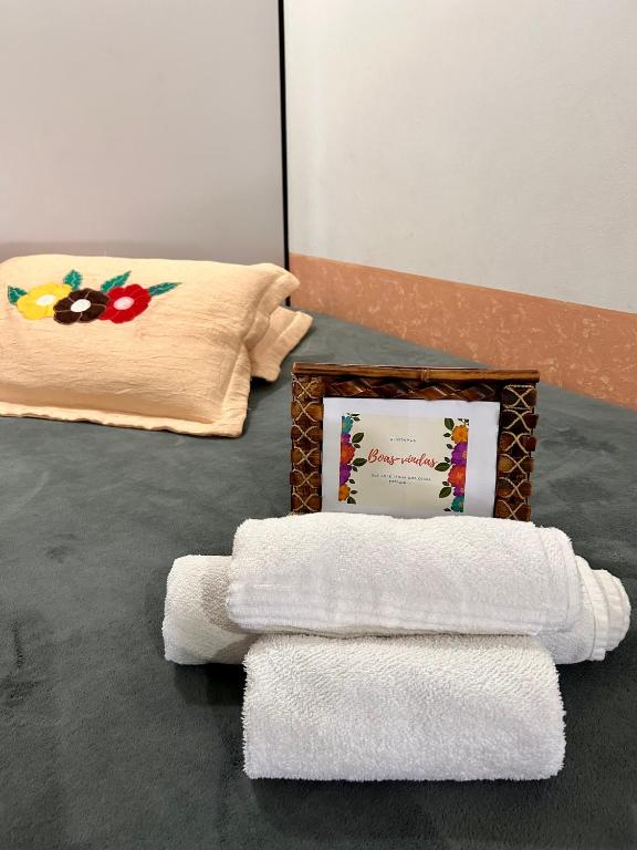 a pile of towels sitting on the floor next to a picture at Quarto confortável em Imbituba in Imbituba