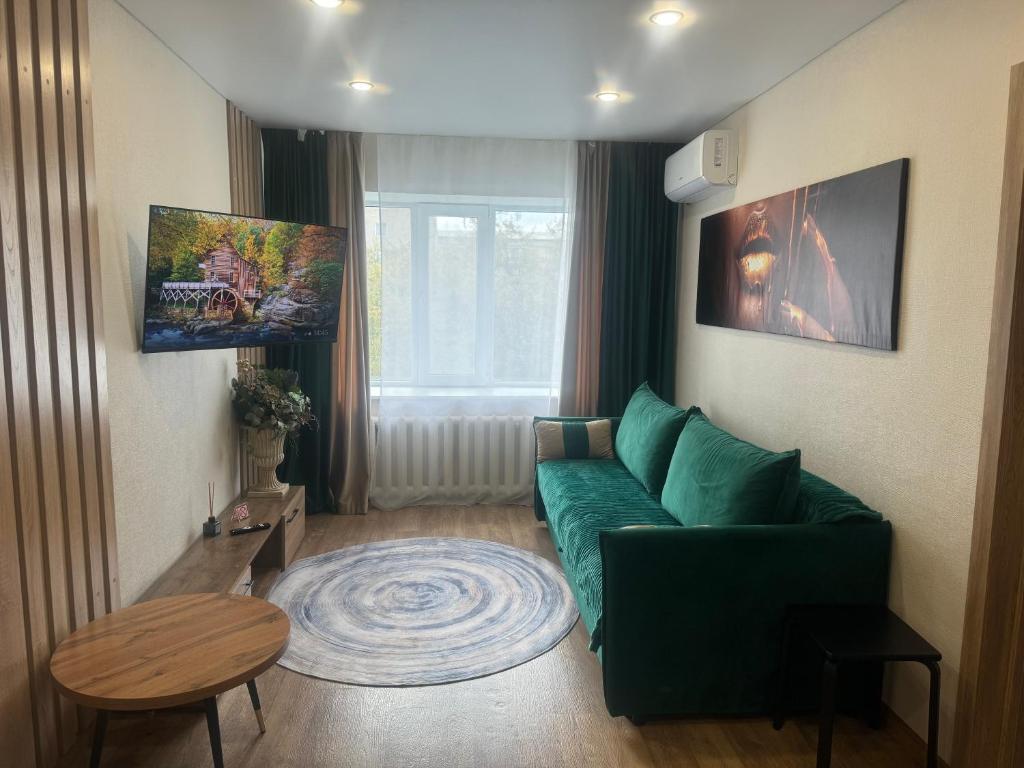 a living room with a green couch and a table at Бухар -Жырау 72 in Karagandy