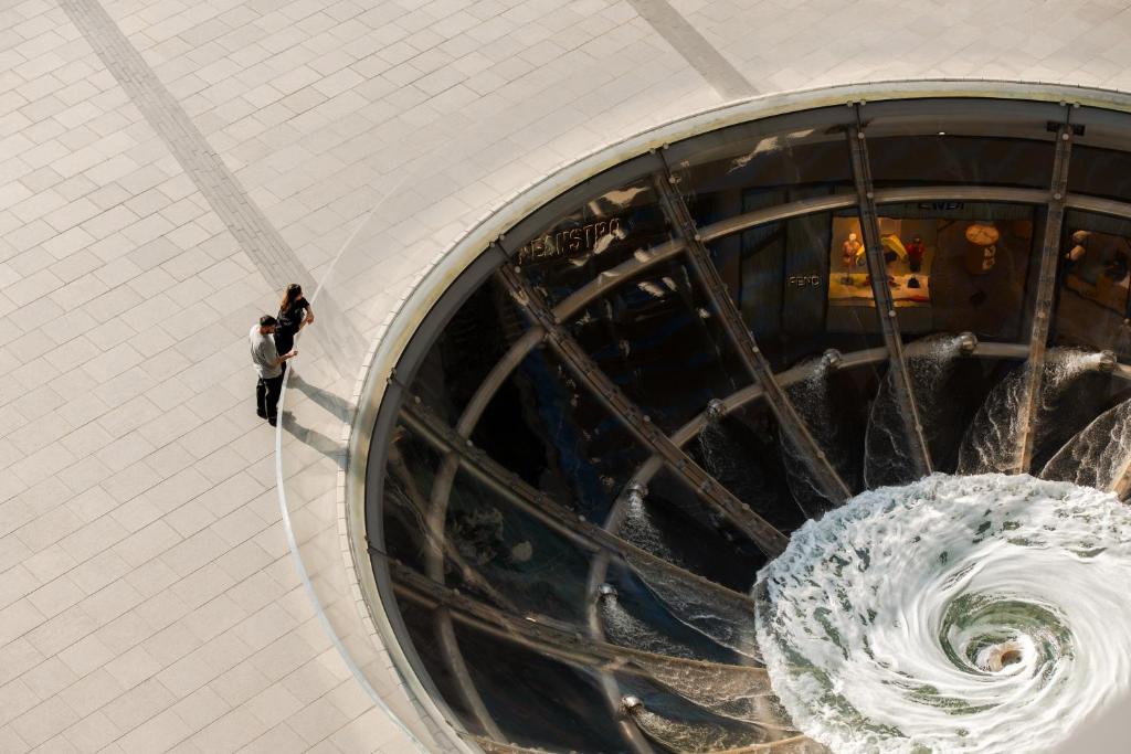 eine Wendeltreppe in einem Gebäude mit einem Wasserfall in der Unterkunft Marina Bay Sands in Singapur