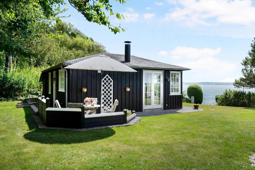 un hangar noir avec une table et des chaises dans l'herbe dans l'établissement Beautiful Holiday Home With Panoramic Views Over Ebeltoft Bay, à Ebeltoft