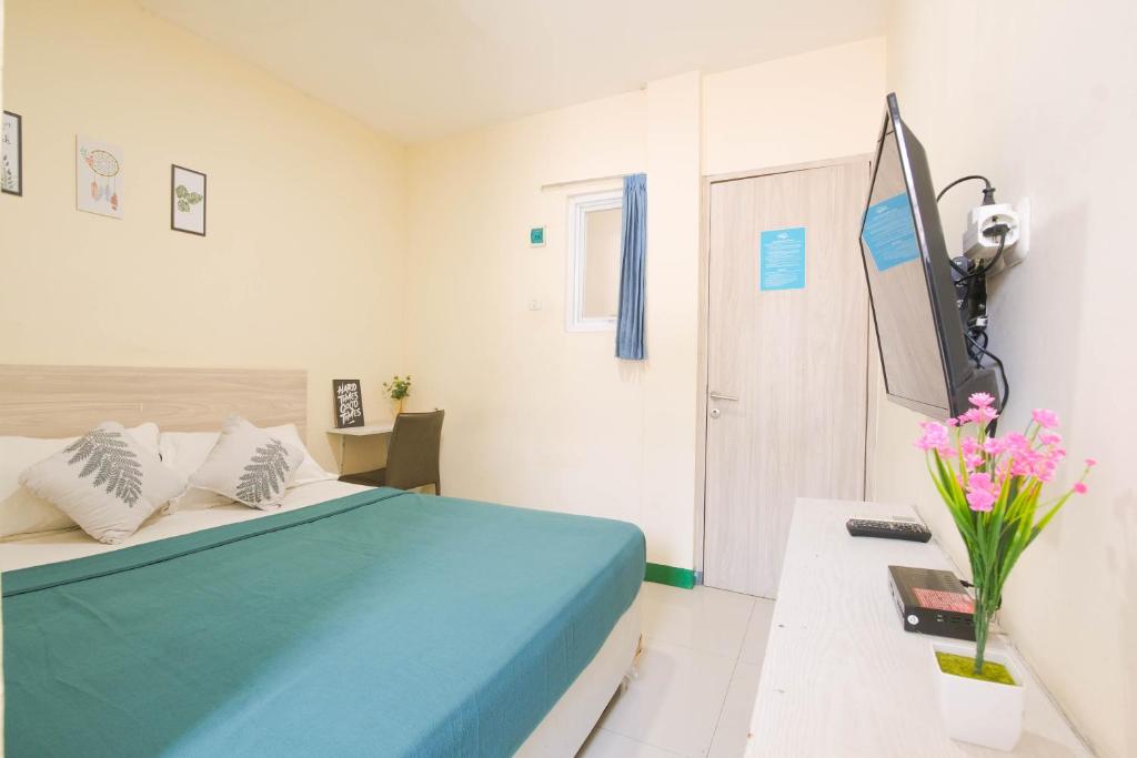 a bedroom with a blue bed and a vase of flowers at Le Paris Syariah Residence in Tangerang