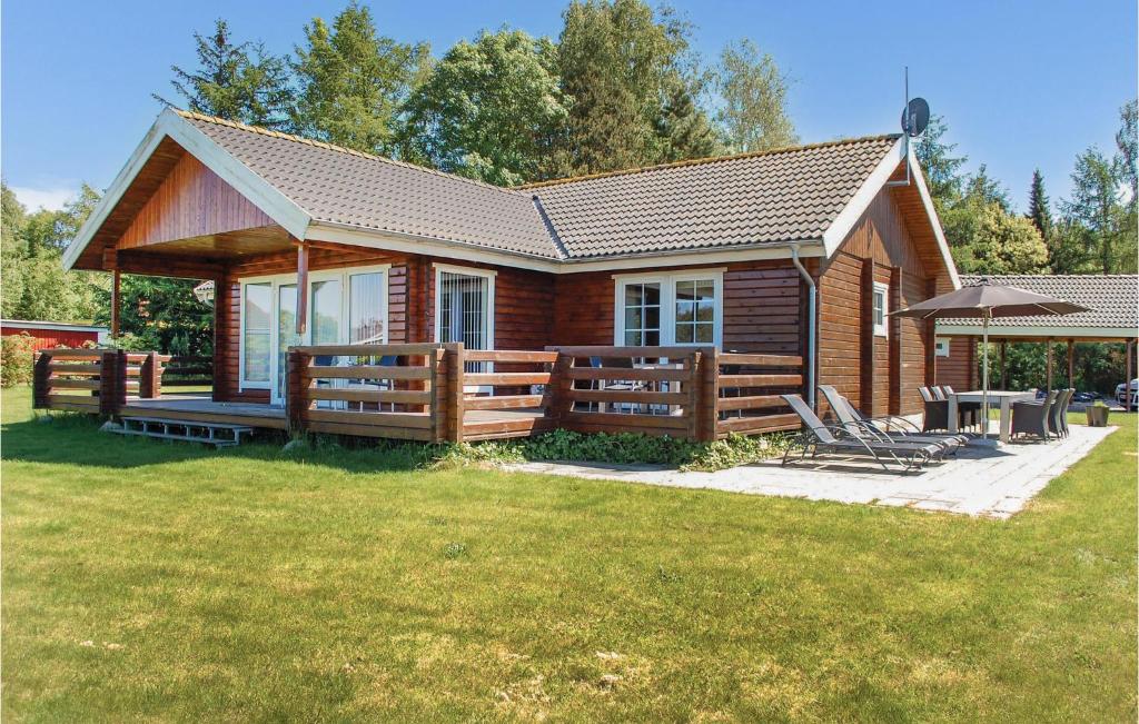 a log cabin with a deck and a table and chairs at Holiday Home Kærsangervej Ebeltoft in Øksenmølle