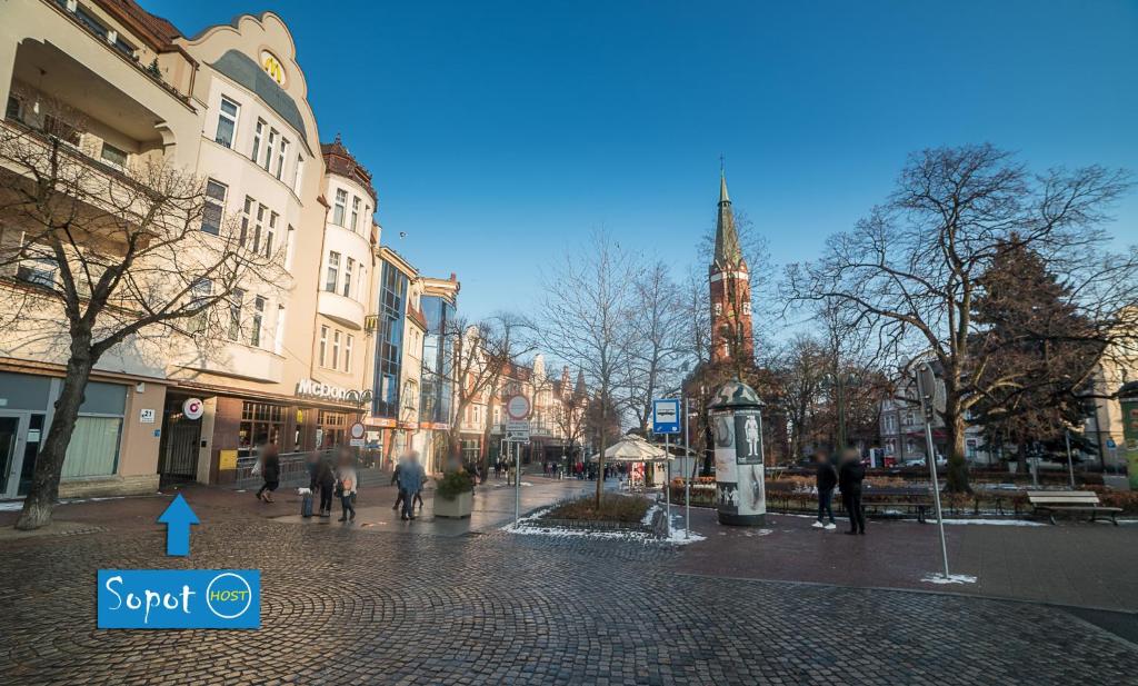 uma rua da cidade com pessoas andando e uma igreja em Sopot Host em Sopot