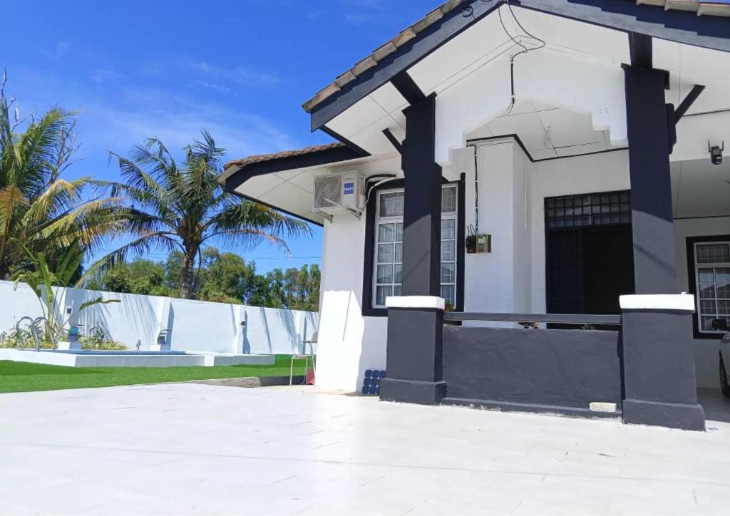 une maison blanche avec une clôture et des palmiers dans l'établissement Caza Cottage Terengganu, à Kampong Gong Badak