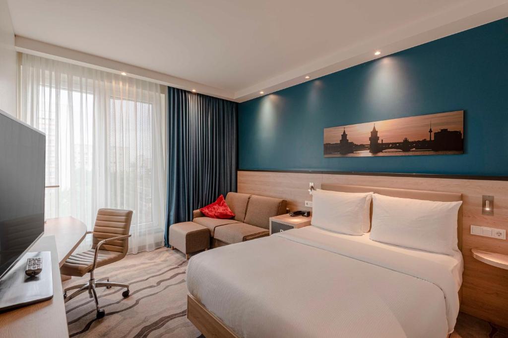 une chambre d'hôtel avec un lit et un canapé dans l'établissement Hampton by Hilton Berlin City Centre Alexanderplatz, à Berlin