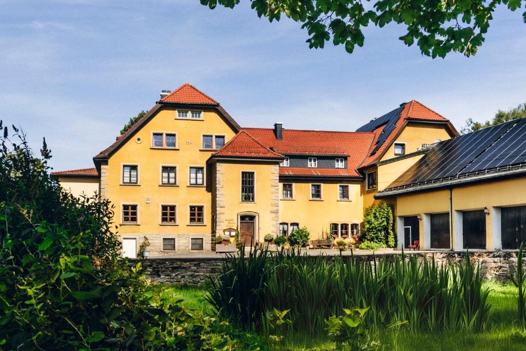 a large yellow house with red roofs at Landgasthof Haueis in Marktleugast