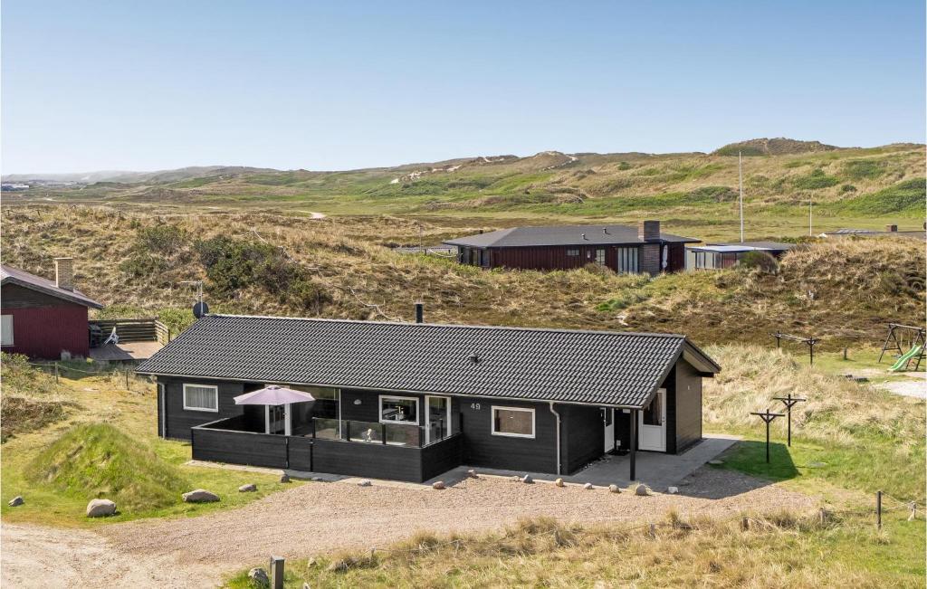 a house with a black roof on top of a hill at Three-Bedroom Holiday Home In Hvide Sande in Bjerregård