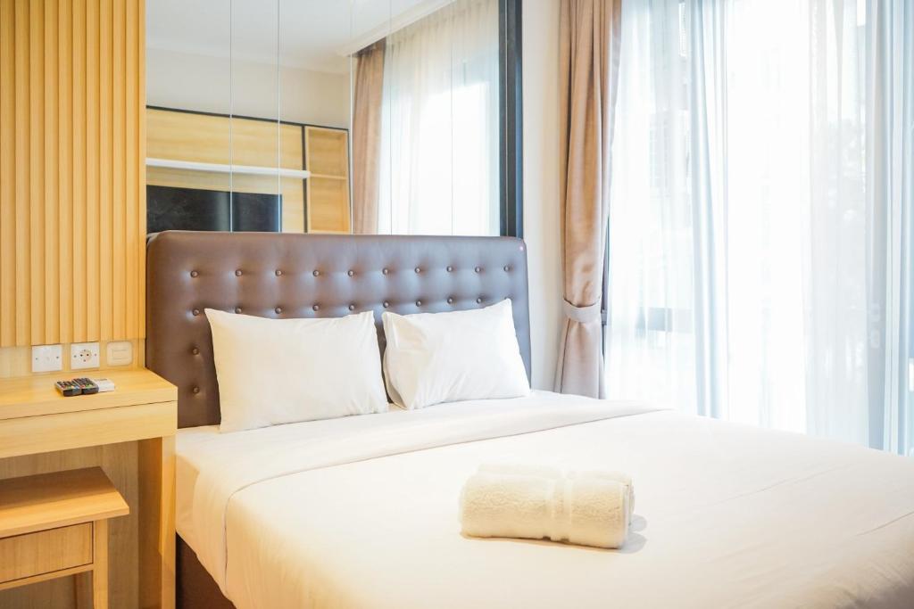 a bedroom with a large bed with a large window at Cozy 3BR Asatti Apartment near ICE BSD By Travelio in Tangerang