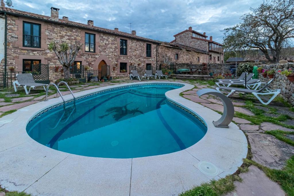 a swimming pool in front of a stone house at La Casona De Barrio in Barrio
