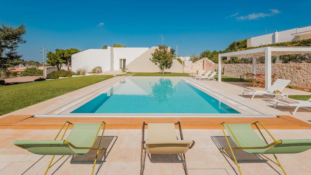 une piscine avec des chaises et une maison dans l'établissement VILLA BELLINA 6, Emma Villas, à Ostuni