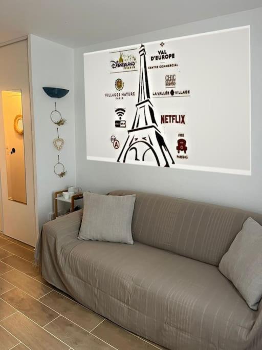 - un canapé dans une chambre avec une photo de la tour Eiffel dans l'établissement Charmant appartement Disneyland Paris 2 pers, à Bussy-Saint-Georges