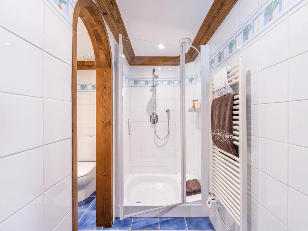 a white bathroom with a shower and a toilet at La Maison Hôtel Les Peupliers in Courchevel