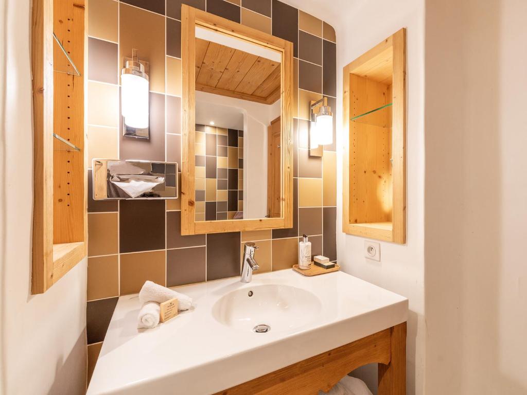 a bathroom with a sink and a mirror at La Maison Hôtel Les Peupliers in Courchevel