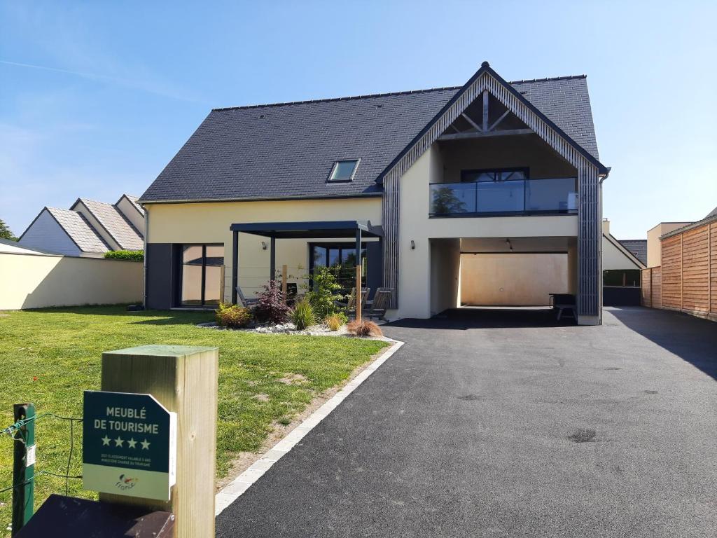 une maison avec un panneau en face d'une allée dans l'établissement Villa Jacuzzi au pied de la Baie du Mont St Michel, à Genêts