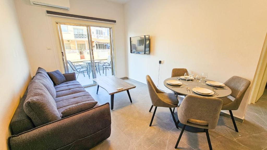 a living room with a couch and a table with chairs at La Magenta Apartments in Pyla