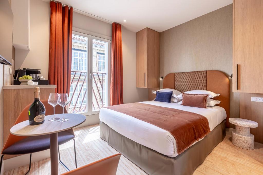 a hotel room with a bed and a table with wine glasses at Suites FL By Sweett in Paris