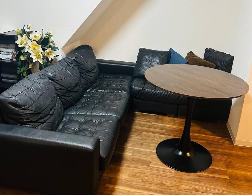 ein schwarzes Ledersofa und ein Tisch im Wohnzimmer in der Unterkunft 京橋駅徒歩10分圏内隠れ宿京橋 in Osaka