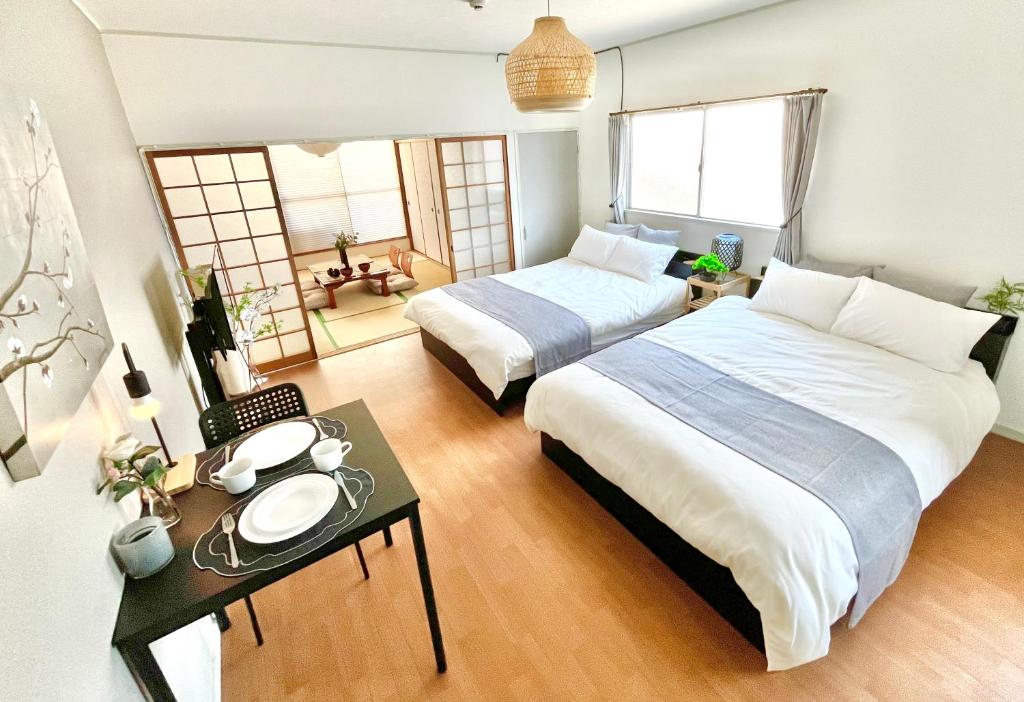 a bedroom with two beds and a table with a table at OMOTENASHI STAY OSAKA 41m2 1LDK 十三駅徒歩1分 梅田2分 神戸京都アクセス良好 和室のある家 in Osaka