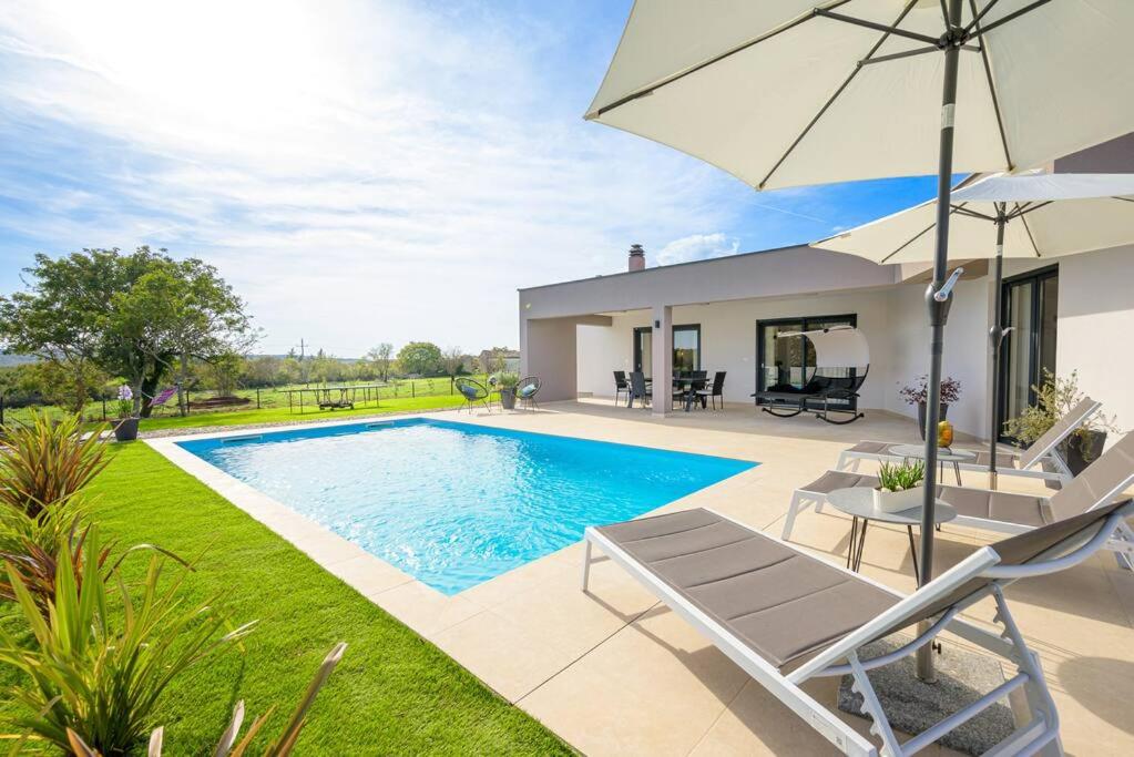 a villa with a swimming pool and an umbrella at Villa Drandic by IstriaLux in Bale