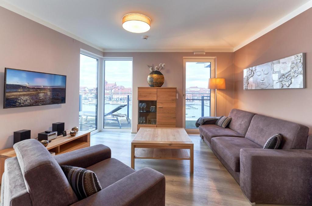 a living room with a couch and a table at Entschleunigung - Apartment mit Dachterrasse & Müritzblick in der Hafenresidenz in Waren