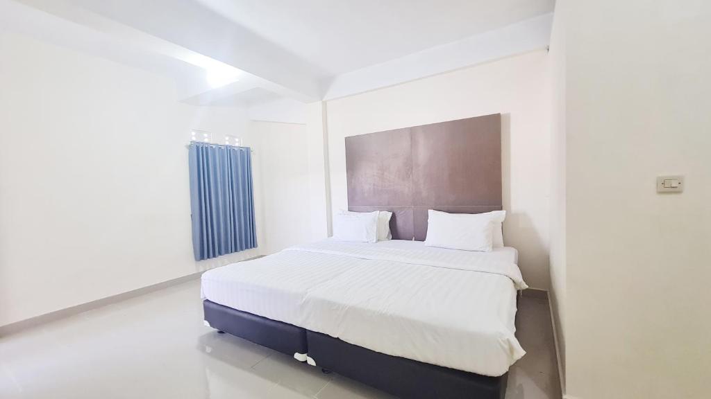 a white bedroom with a large bed in it at Homestay Tasya in Labuan Bajo