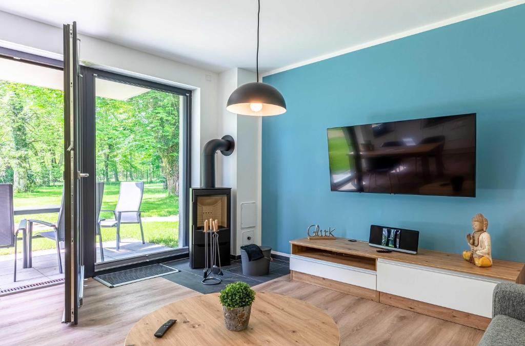 Una sala de estar con un televisor y una mesa. en Zuversicht Ferienwohnung am Krakower See Komfort & Wellness mit Seeblick, en Krakow am See
