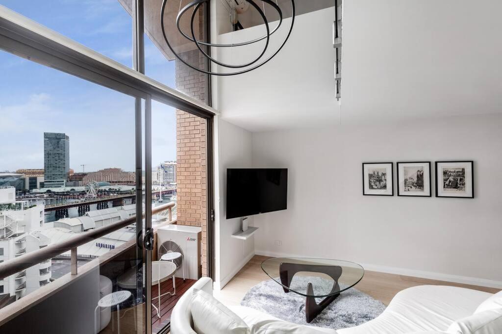 a white living room with a balcony with a tv at KozyGuru Sydney CBD Harbor View Loft with Parking in Sydney