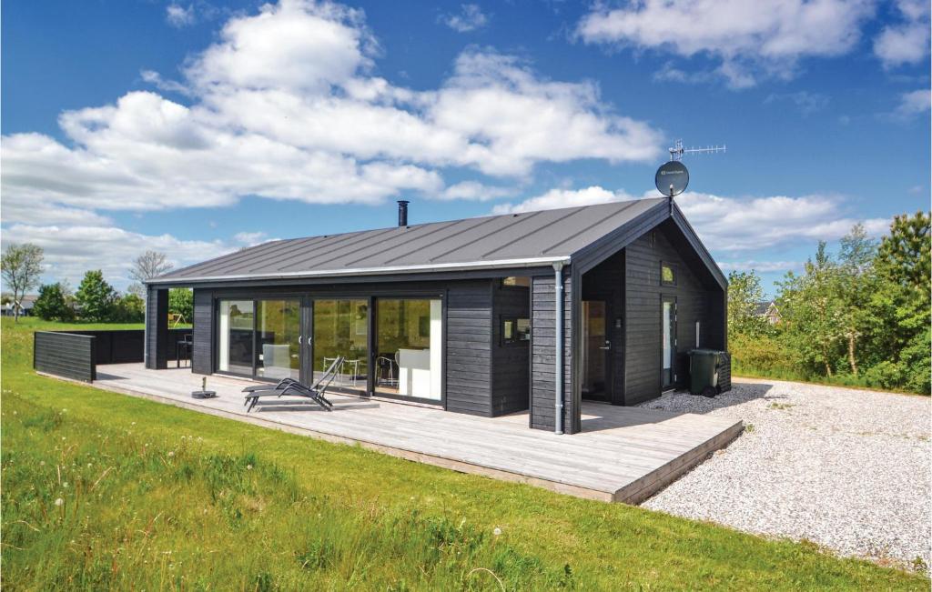a black cabin with a deck in a field at Three-Bedroom Holiday Home In Grenaa in Grenå
