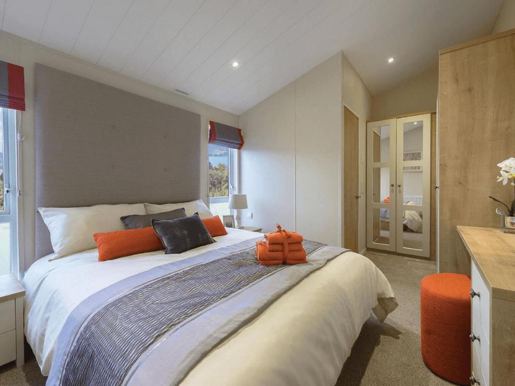 a bedroom with a large bed with orange pillows on it at Limetree Lodge 2 at Thurston Manor Leisure Park in Dunbar