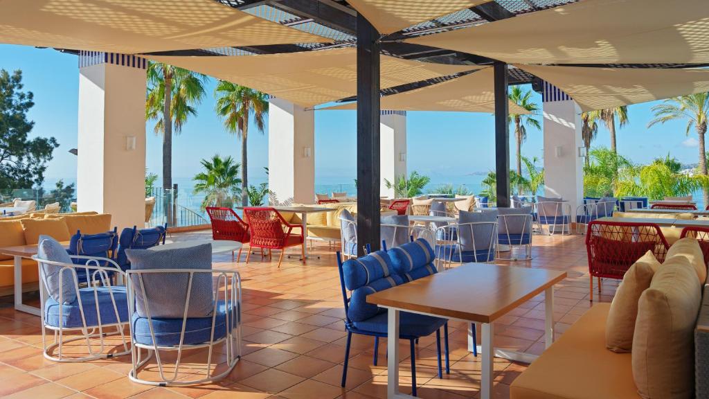 a restaurant with tables and chairs and palm trees at H10 Estepona Palace in Estepona