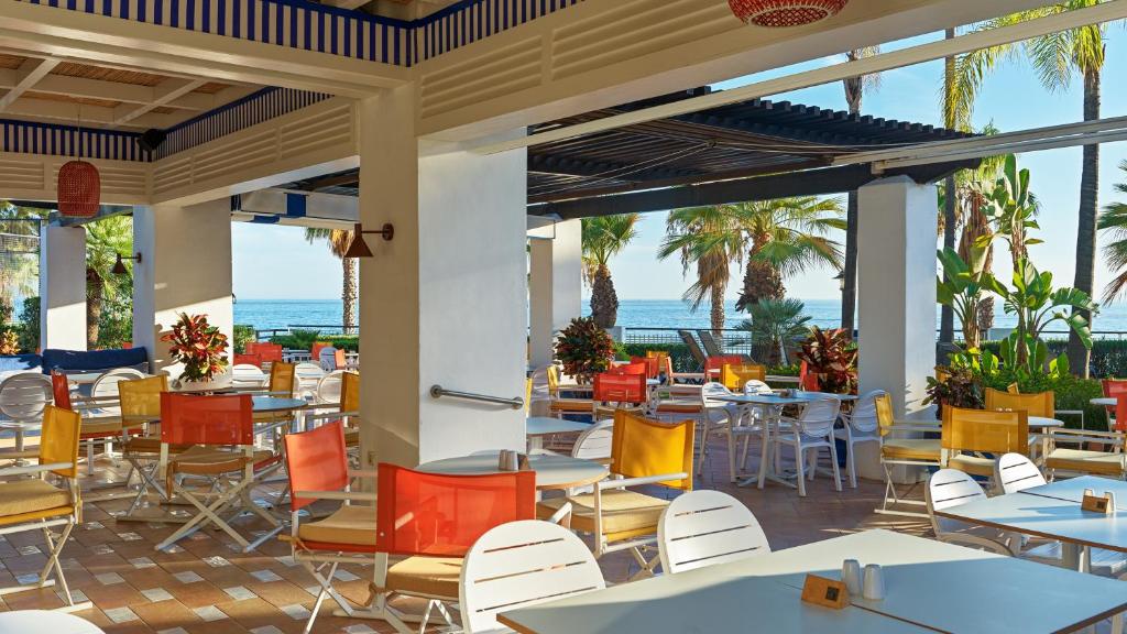 a restaurant with tables and chairs with the ocean in the background at H10 Estepona Palace in Estepona