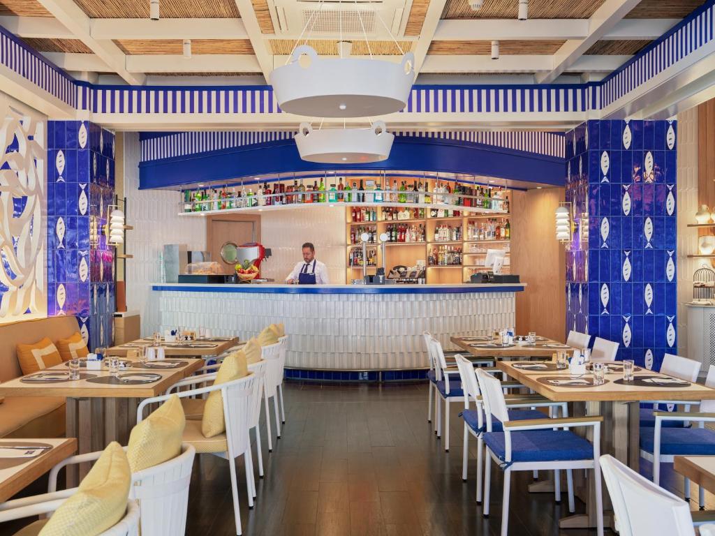a restaurant with blue walls and white tables and chairs at H10 Estepona Palace in Estepona