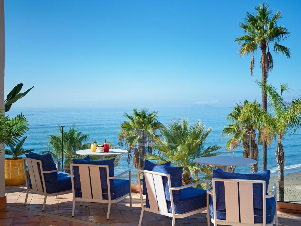 a patio with chairs and tables and the ocean at H10 Estepona Palace in Estepona