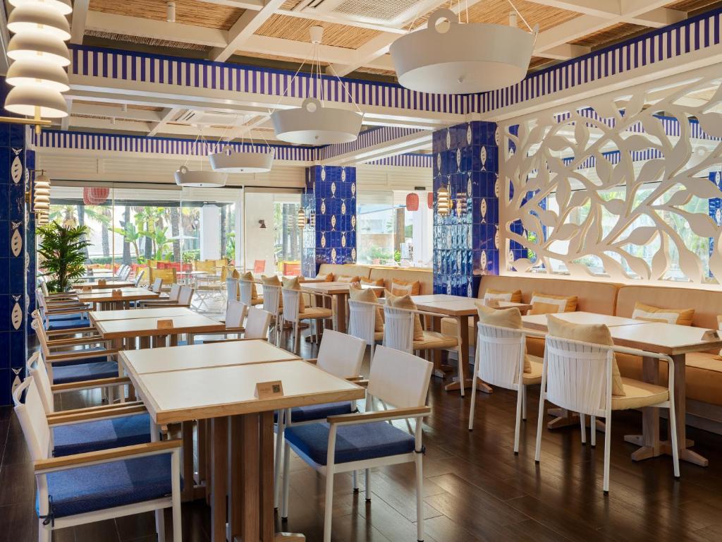 a dining room with tables and chairs in a restaurant at H10 Estepona Palace in Estepona
