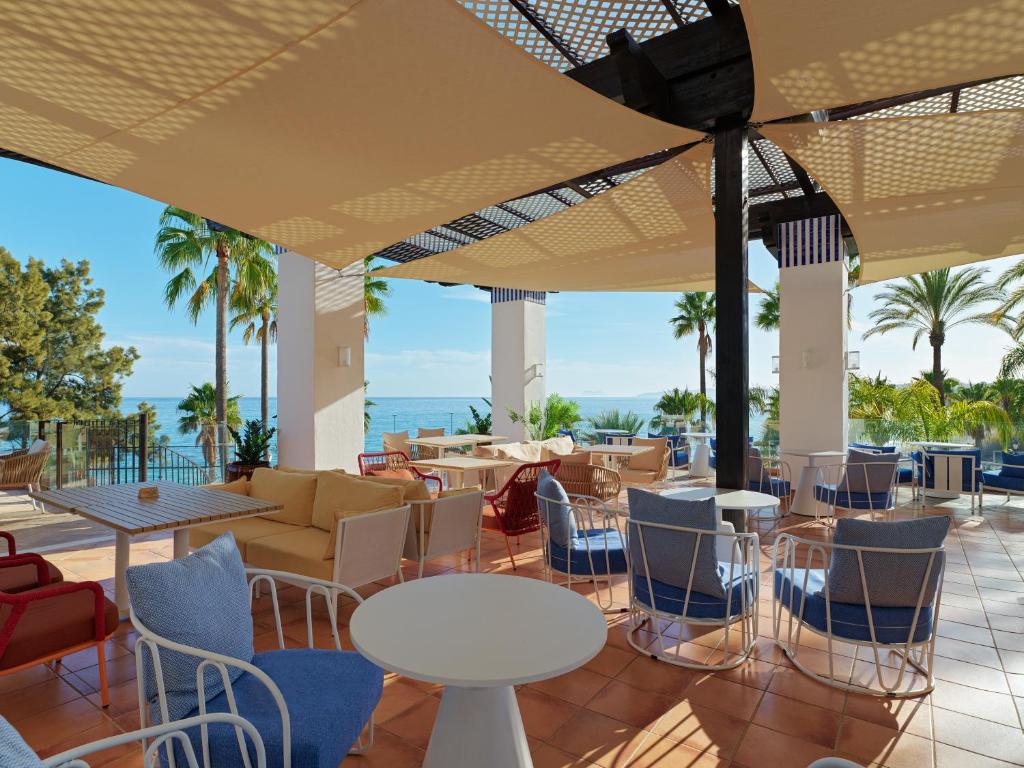 a patio with tables and chairs and the ocean at H10 Estepona Palace in Estepona