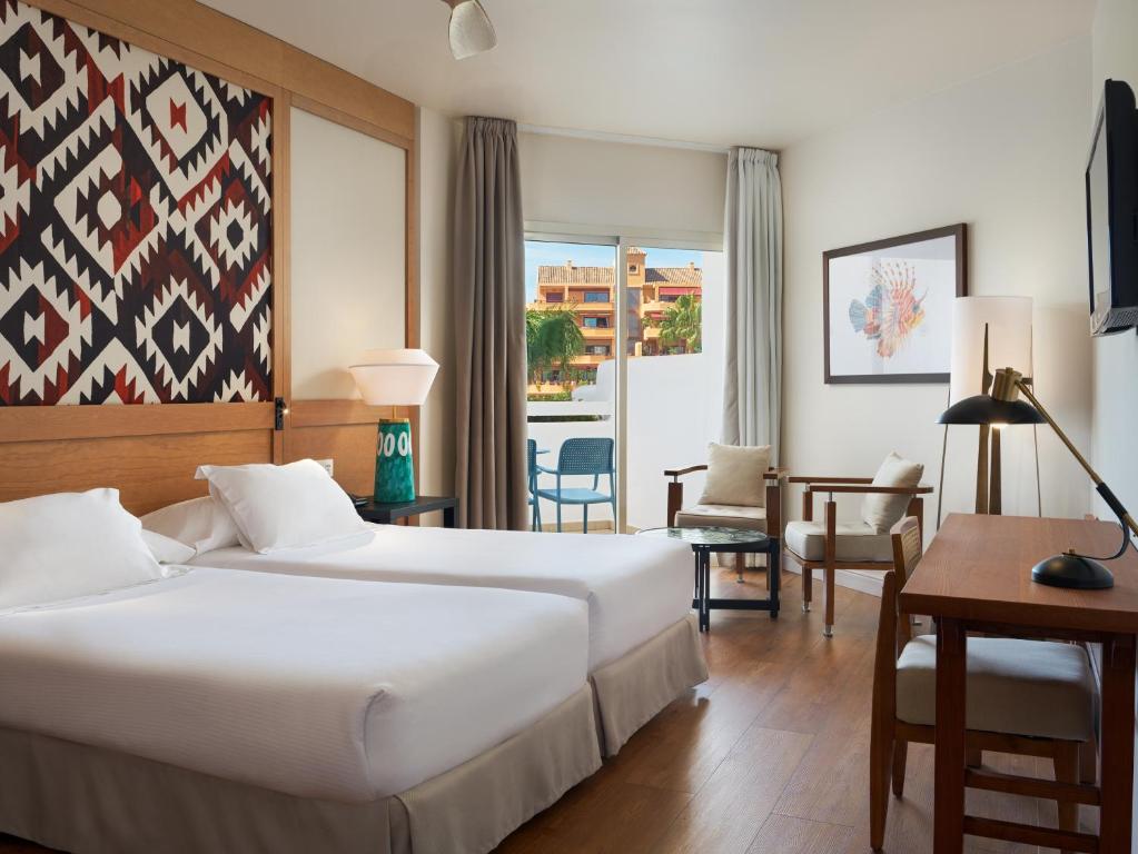 a hotel room with two beds and a table and chairs at H10 Estepona Palace in Estepona