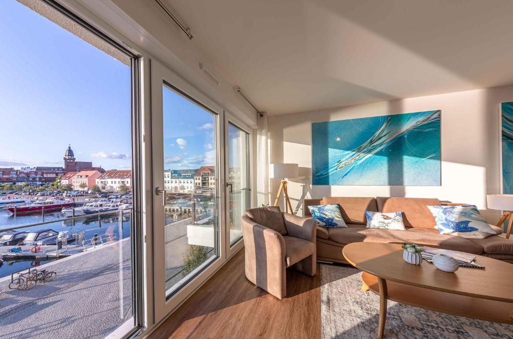 ein Wohnzimmer mit Couch und großem Fenster in der Unterkunft Hafenperle - Apartment mit Balkon & Wellnessbereich in der Hafenresidenz in Waren (Müritz)