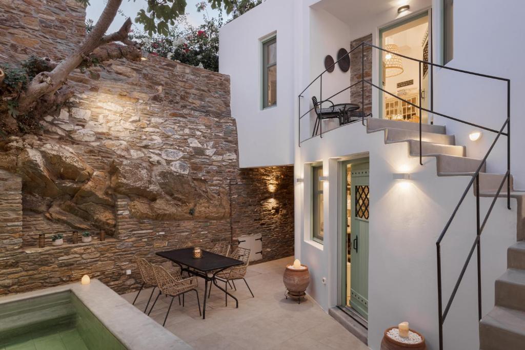 a patio with a table and stairs next to a brick wall at Porto Sereno Andros Suites in Andros