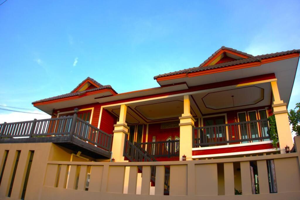 a red house with a balcony on top of it at AkiraSunRice Villa calme, jardin et rizières in Phra Nakhon Si Ayutthaya