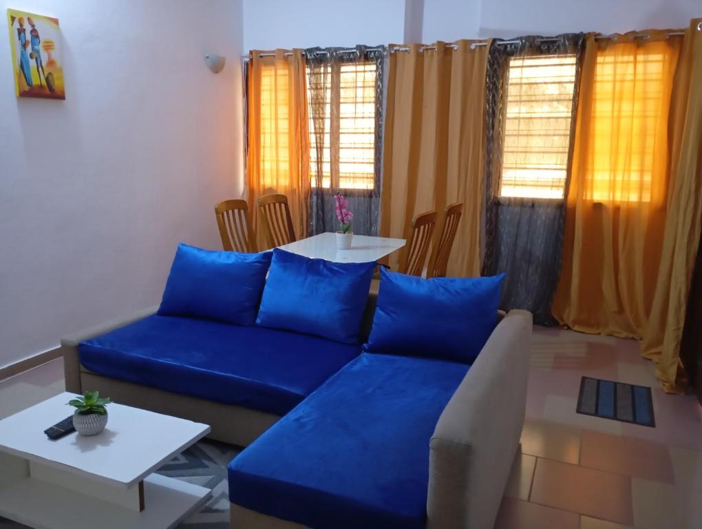 un soggiorno con un divano blu e un tavolo di Jrodait appart a Cotonou