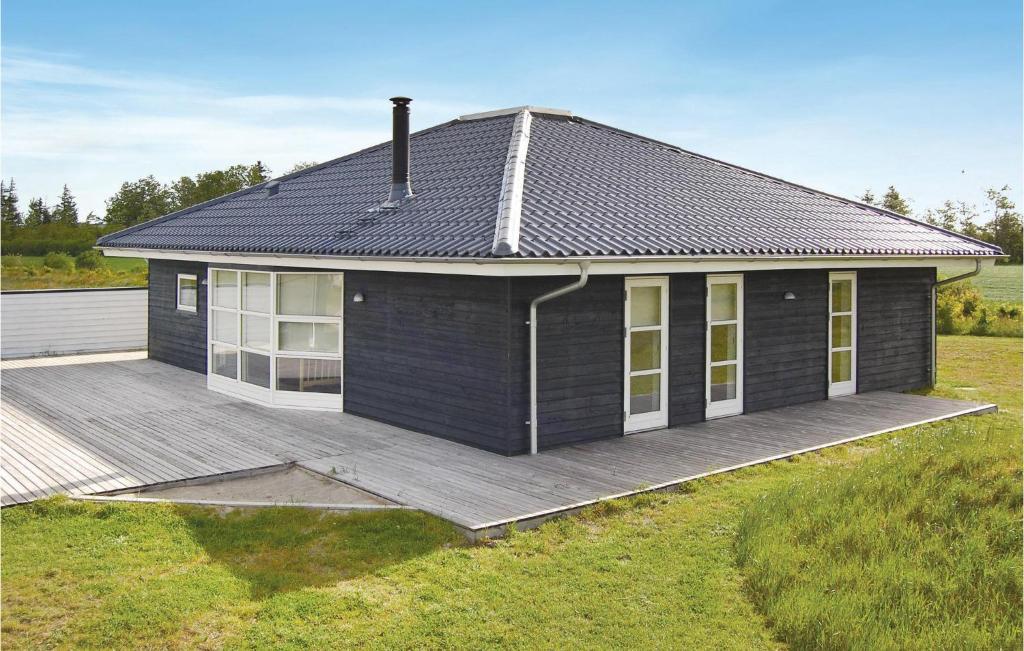 a small house with a wooden deck in a field at Holiday Home Stikkelsbærvej Tarm Iv in Hemmet