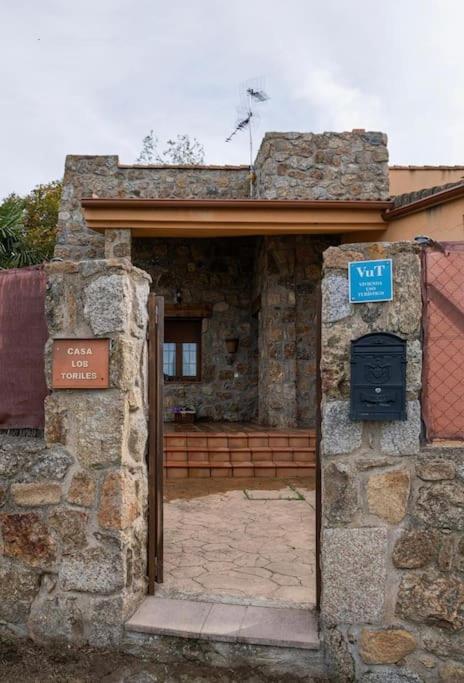 an entrance to a stone building with a blue sign at Casa los toriles in Ortigosa del Monte
