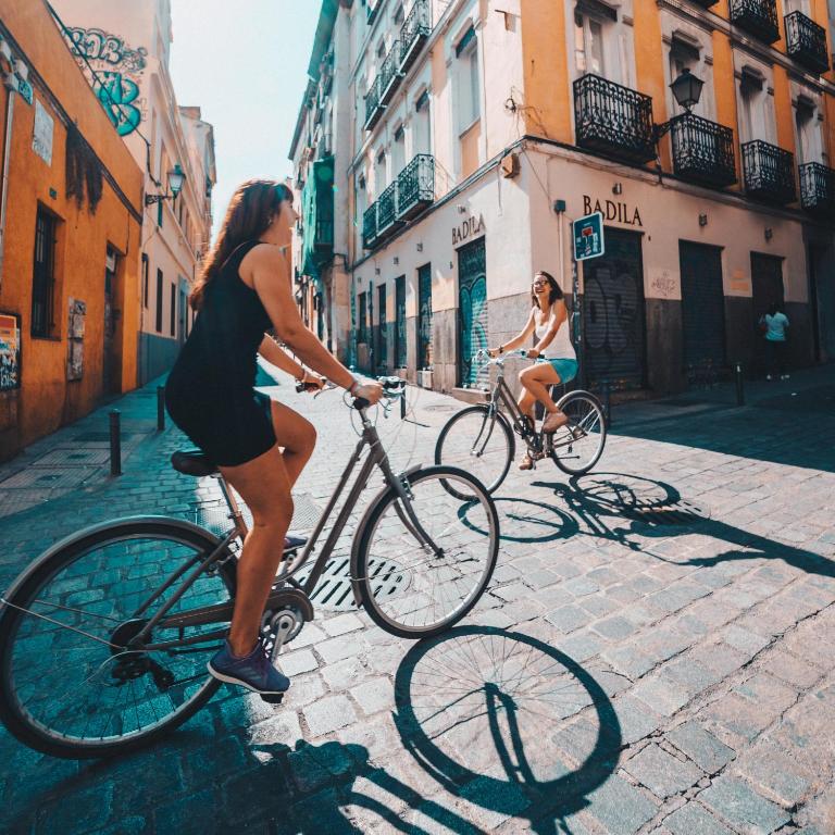 dos mujeres montando en bicicleta por una calle de la ciudad en 2060 The Newton Hostel, en Madrid