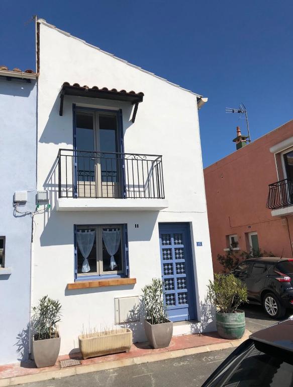 - un bâtiment blanc avec un balcon et une fenêtre dans l'établissement Petit nid coquet à la Pointe Courte, à Sète