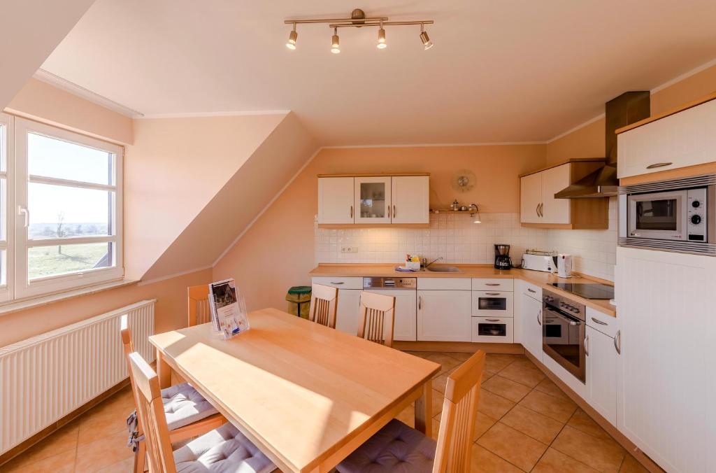 a kitchen with white cabinets and a wooden table at Storchenflug - Dachgeschosswohnung mit Kamin & Balkon am Fleesensee in Göhren-Lebbin