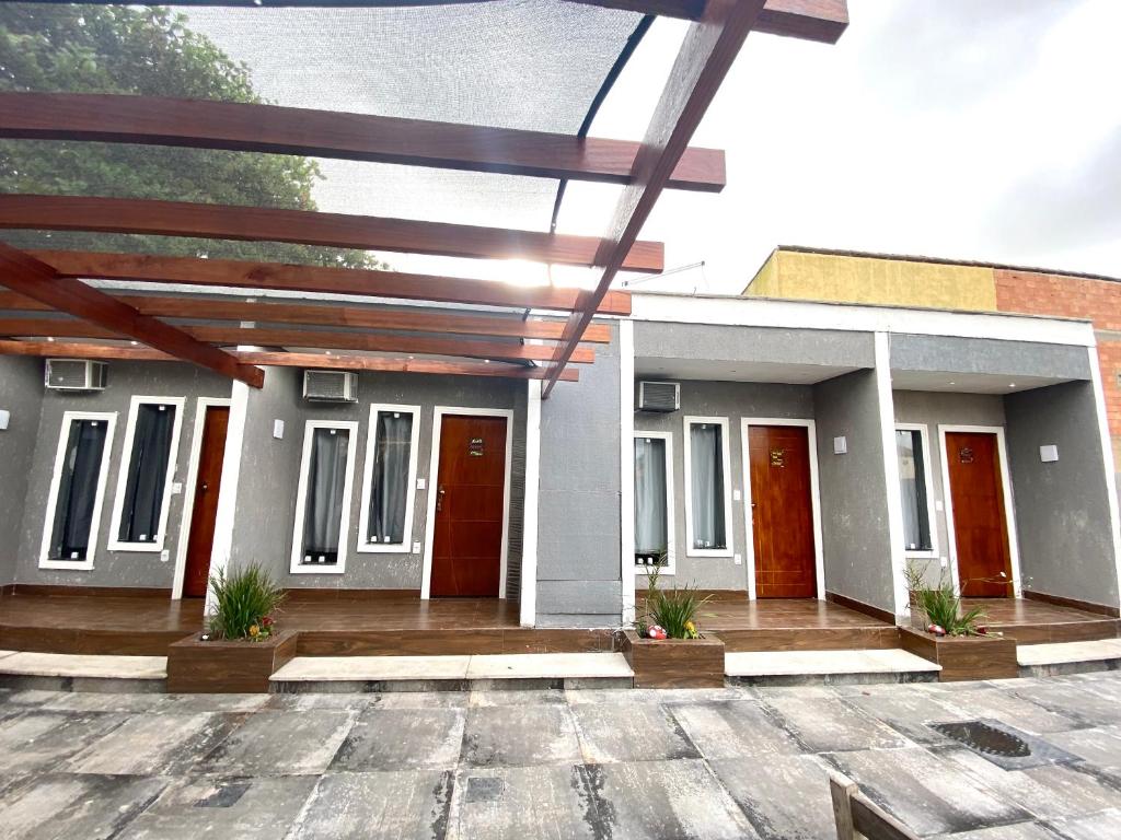 a house with red doors and a patio at Pousada Recanto Beach House - Cabo Frio - RJ- Unamar- Cond Florestinha - 1 min a pé da praia in Tamoios