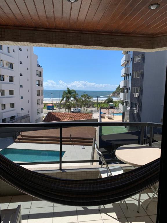 a balcony with a hammock and a view of the ocean at Caioba Apto Confortavel in Matinhos