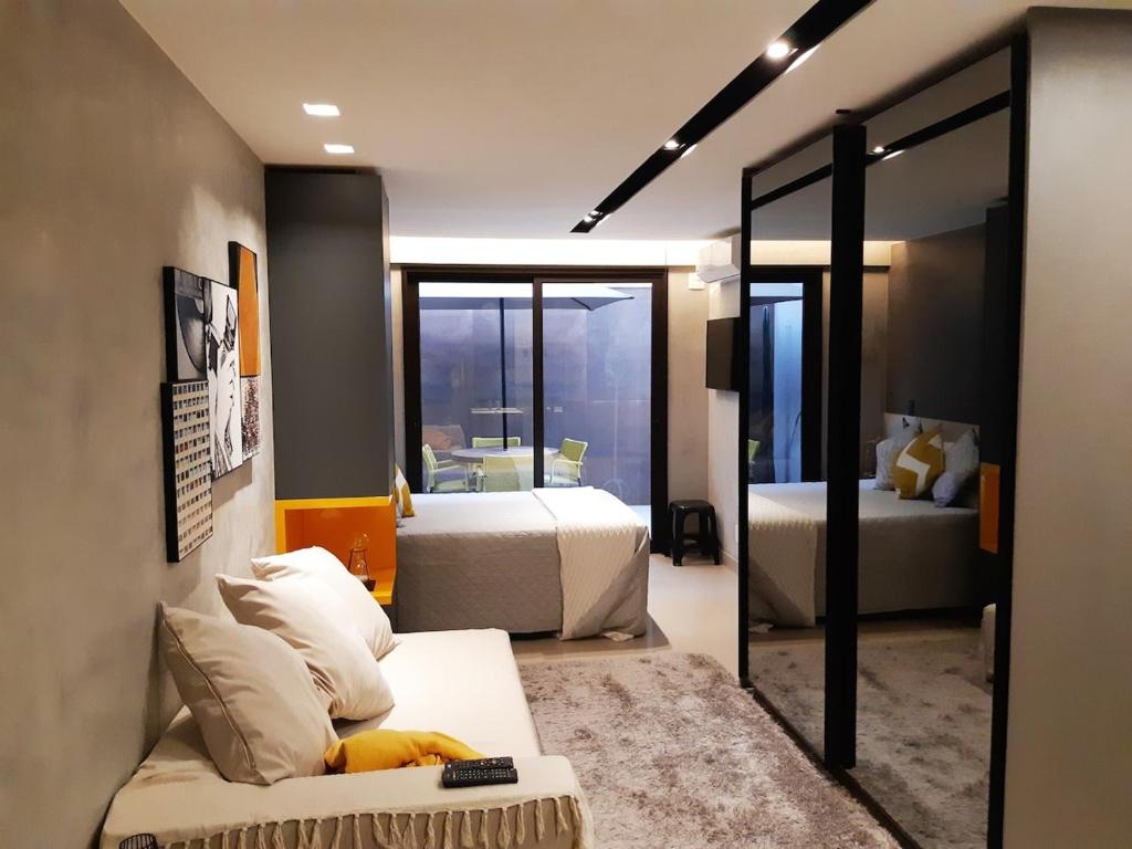 a bedroom with two beds and a couch and a mirror at Soul Housing & Shop · Studio com varanda. Noroeste. Soul Housing & Shop in Brasilia
